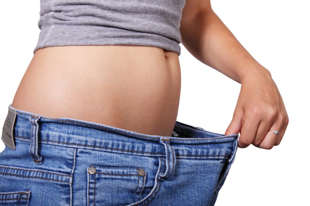 Image of a woman's waist and jeans that are too big for her